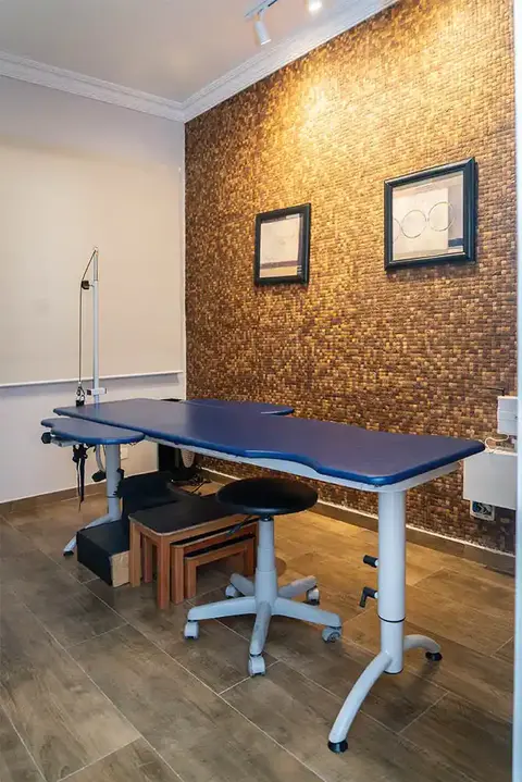 Sala de terapia com maca de RPG e mesa de escritório