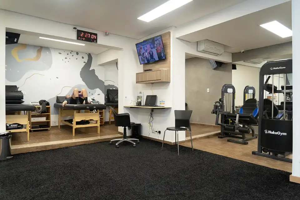 Salas com equipamentos de musculação, macas e gramado para treino funcional.