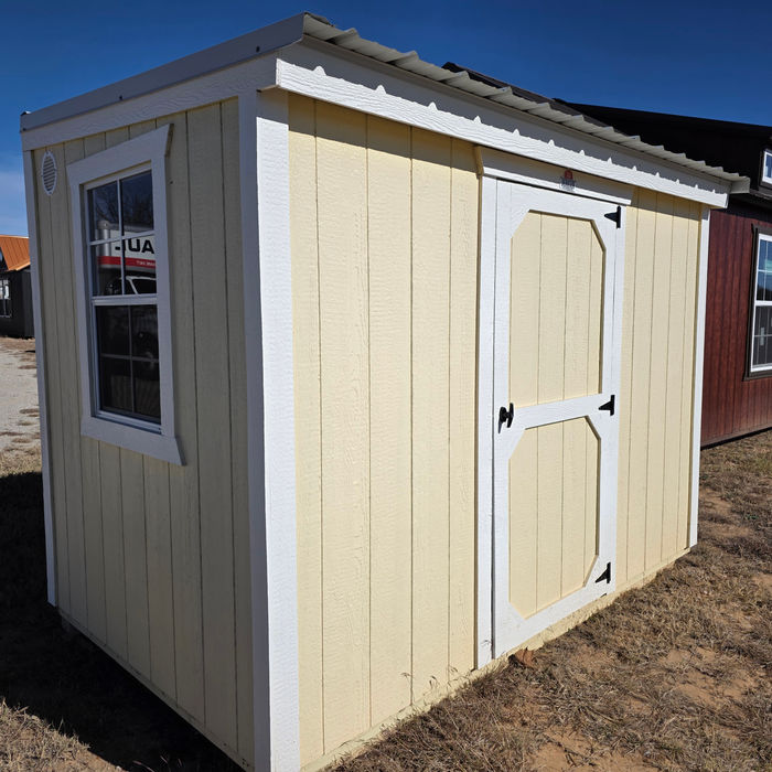 Beige Metro shed with white double doors, side window, and white trim, shown on a dirt/gravel surface.