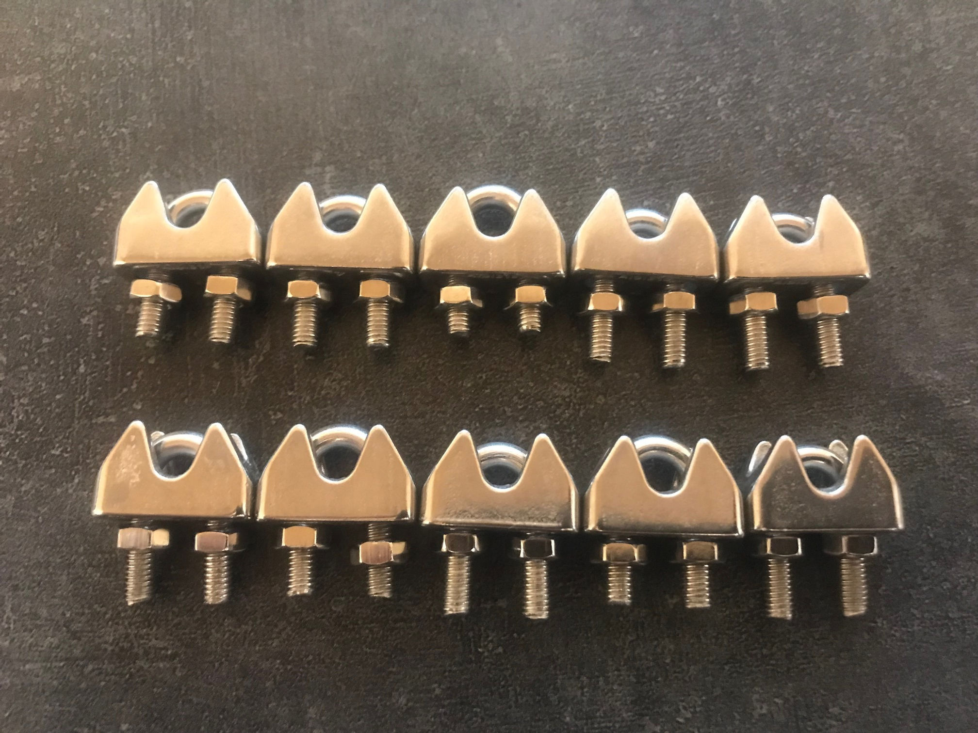 Plusieurs pinces métalliques posées sur une surface foncée, Métal brut