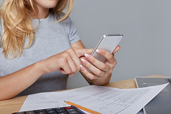 unrecognizable-woman-holds-modern-mobile-phone-hands-sits-work-table-surrounded-with-docum