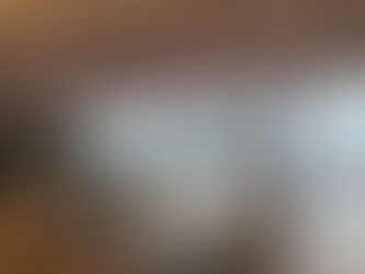 Contemporary office interior with modular tables, ergonomic task chairs, wood flooring, acoustic ceiling panels, and large windows overlooking the city.