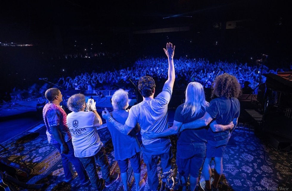 Eye-level view of a vibrant outdoor music festival featuring a jam band performance