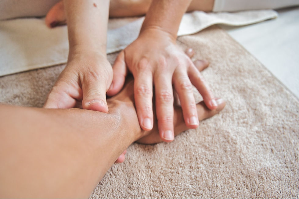 Two hands pressing gently around another person's hand and wrist, resting on a folded towel