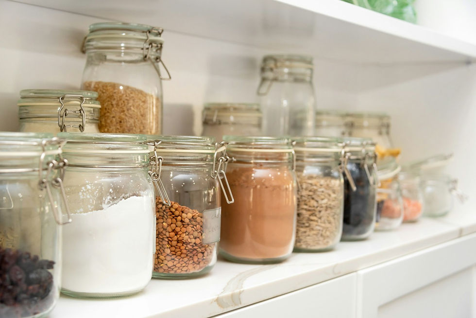Sealed glass jars filled with dry pantry goods lined up along a white kitchen shelf