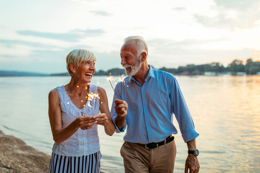 Older couple laughing and playing with sparklers at the beach in Florida