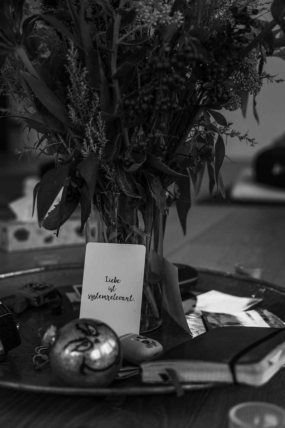 Karte mit der Aufschrift „Liebe ist systemrelevant“ neben persönlichen Gegenständen – Symbol für Trauergruppen, Erinnerung und Verbindung trotz Verlust