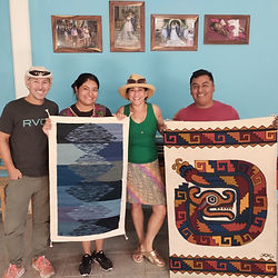 Artisans proudly displaying handwoven rugs alongside happy visitors in Teotitlán del Valle, celebrating the cultural exchange and craftsmanship.