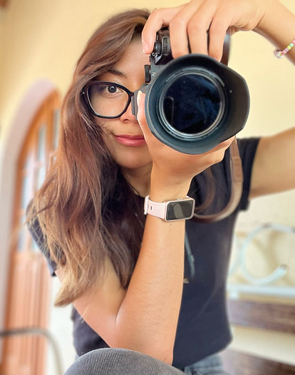 Yara, smiling and holding a camera, capturing a moment during a city walking experience in Oaxaca.