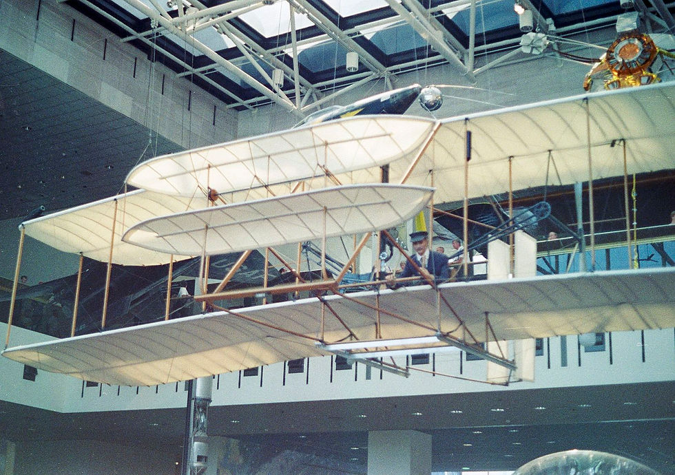 Early Wright Flyer biplane on display at the National Air and Space Museum, showing its wooden frame, fabric wings, and twin propellers — an iconic example of the Wright Brothers’ pioneering aircraft design.
