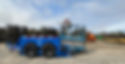 Blue trailer with bed lowered to ground with scissor lift being loaded.