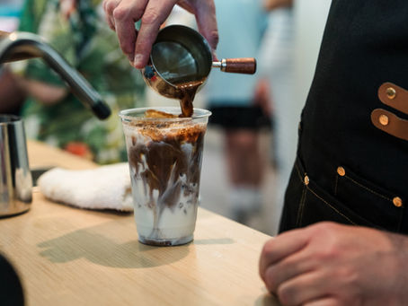 Barista at coffee cart pouring an iced coffee.