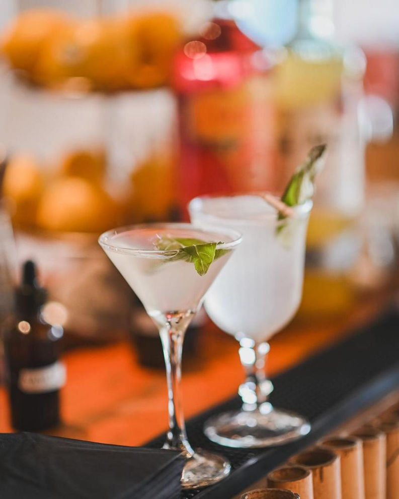 שני קוקטיילים, אחד בכוס מרטיני עם נענע, על דלפק בר.