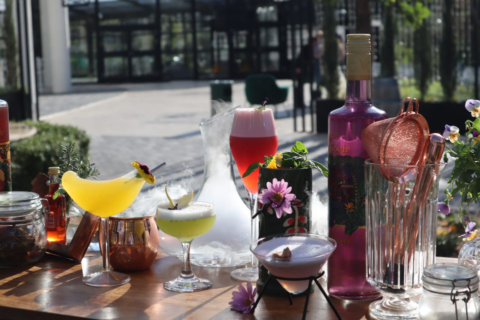 קוקטיילים ססגוניים עם עשן יבש, בקבוקים וכוסות, בבר חיצוני.