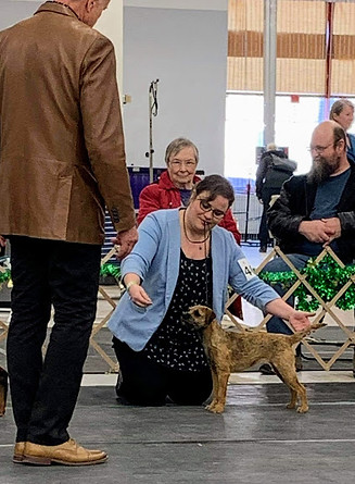 A woman showing her dog to a judge