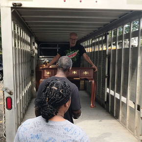 Volunteers wait as our furniture man carries a piece of furniture to them from his truck.