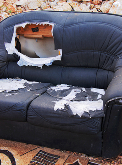 Picture of a beat up, broken, delapidated loveseat.