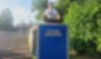 A teenage boy who is a volunteer sitting on top of our clothing donations bin, thumb's up, smiling, wearing a t-shirt that says "Is That All You Got?"