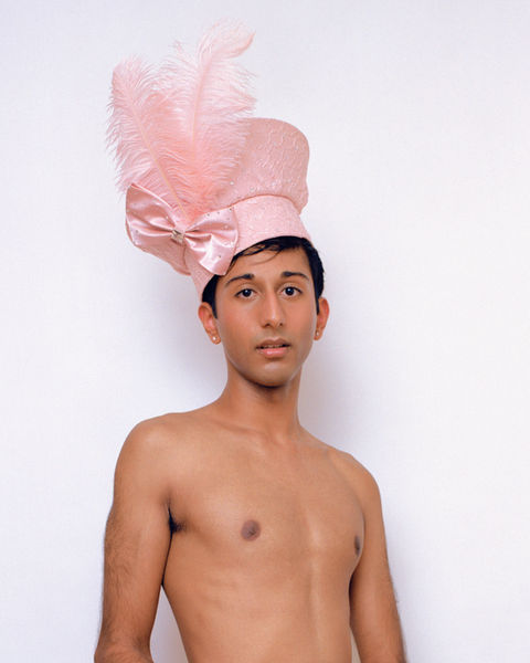 Kush wearing a pastel pink church hat with pink feathers, pink bow, and bedazzled gems. Indian boy wears a pink feathery hat. photographed on 120mm kodak portra 400 film.