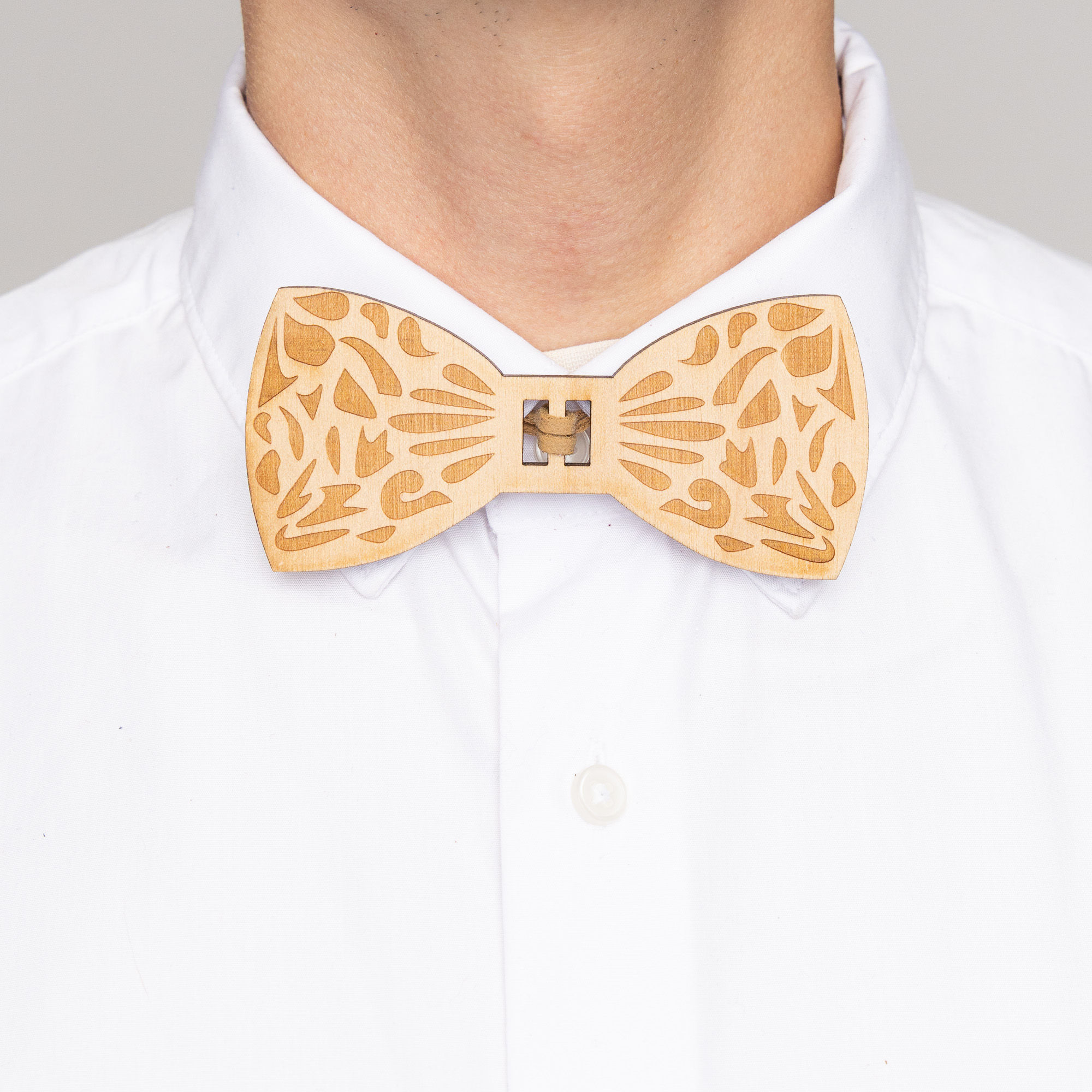 Laser-engraved wooden bow tie with paisley pattern and tan faux suede center, designed by Daniel Roa front