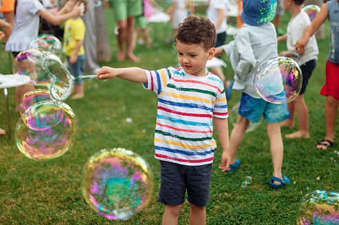 the child inflates large soap bubbles. Street animation program, happy child on a green la