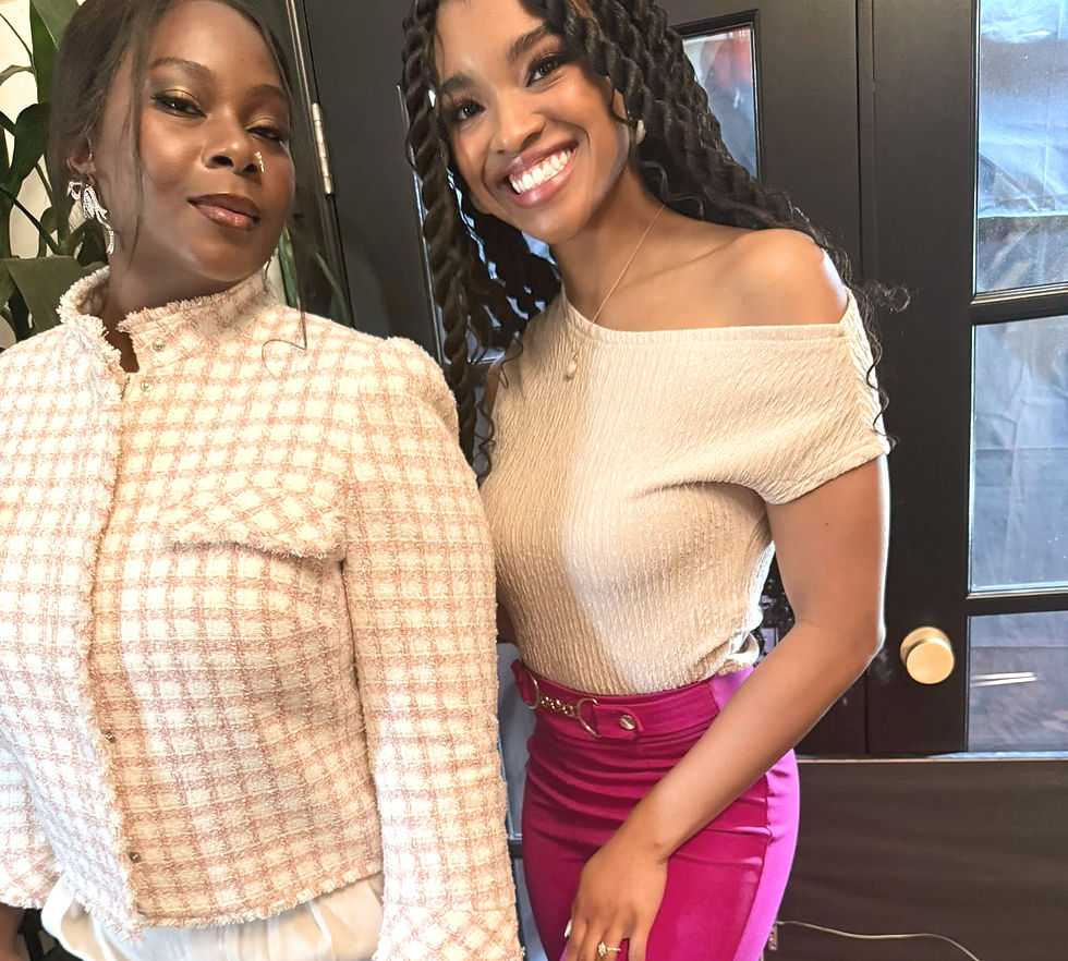 Beula (Precious Oginni) and Tangle (LaYauna Bonds) stand side by side, glowing with confidence and style. One wears a blush-toned tweed jacket with ivory pants and holds a colorful phone case; the other wears a champagne off-shoulder top paired with bold fuchsia pants. Their hairstyles and makeup highlight the beauty and diversity of Black skin, reflecting the essence of The Caste of Beula's vision for grace, strength, and elegance.