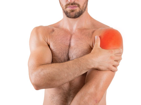 Homme torse nu tenant son épaule douloureuse, symbole d’une douleur ou d’une raideur à l’épaule.