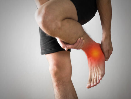 Homme tenant sa cheville douloureuse avec une inflammation visible, illustrant la douleur typique d’une entorse.