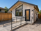 ADA-compliant 499 sq ft detached ADU in Sunnyvale, California featuring a cathedral ceiling design, wheelchair-accessible ramp with handrails, spacious level landing, modern stucco exterior, energy-efficient windows, and expansive paved patio. Custom detached accessory dwelling unit designed for accessible living and multigenerational housing in Santa Clara County.