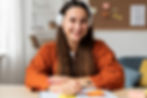 A woman is smiling at the camera holding a pen and wearing headphones
