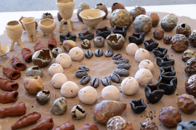 Various ceramic sculptures with different shapes and colors, arranged on a surface.
