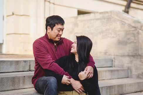 Couple sitting on steps at UT Austin, smiling at each other during their family photo session.