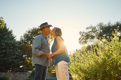 Couple sharing a soft kiss in the golden morning light at Sunken Garden Georgetown TX, celebrating 45 years of marriage.