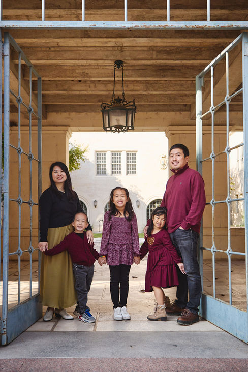 Family of five framed by an archway at UT Austin during their campus photo session.