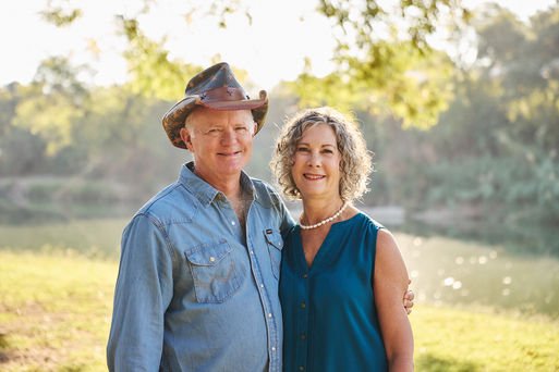 Happy couple standing together by the San Gabriel River during their Georgetown TX anniversary photoshoot, surrounded by morning light and trees.