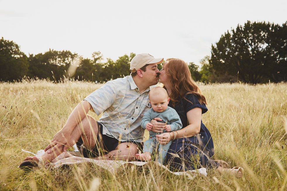 Baby boy sitting with kissing parents at Mary Moore Searight Metropolitan Park.