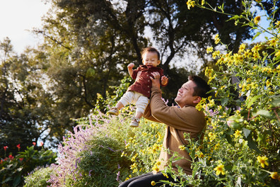 Father lifting his baby surrounded by colorful flowers at Zilker Botanical Garden, Austin. Joyful family moments in natural light.