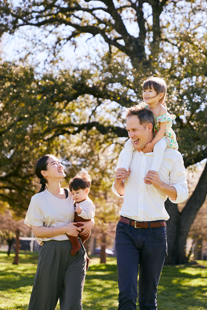 Parents carrying child on shoulders during relaxed family photo session in Austin, Texas park