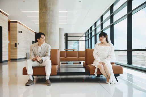 Couple sitting apart and smiling at each other inside the modern interior of the Travis County Courthouse in downtown Austin