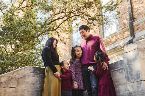 Family of five standing close together on stone steps at UT Austin, sharing a warm and happy moment.
