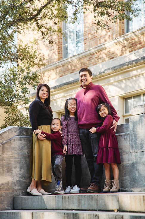 Family of five standing together on the stone steps at UT Austin with warm natural light.