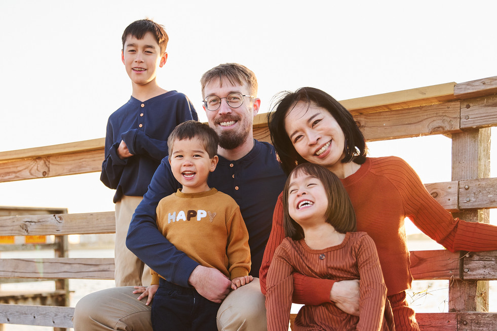 Smiling family portrait on a wooden deck at Lake Pflugerville Park, North Austin family photographer