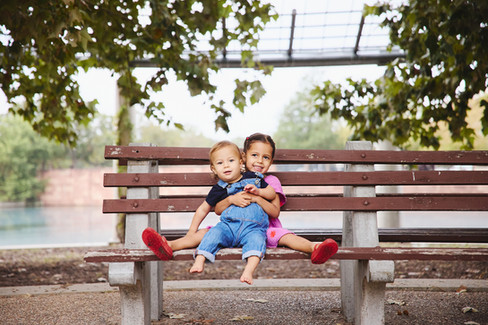 Siblings sitting together on a park bench at Mueller Lake Park during a fall family session.