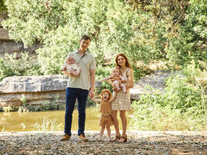 Bull Creek District Park family photos of a family with twin baby girls and an older daughter standing together by the creek in Austin, Texas