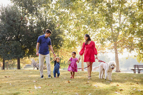 Family walking together at Mueller Lake Park in Austin, surrounded by fall trees and soft morning light.