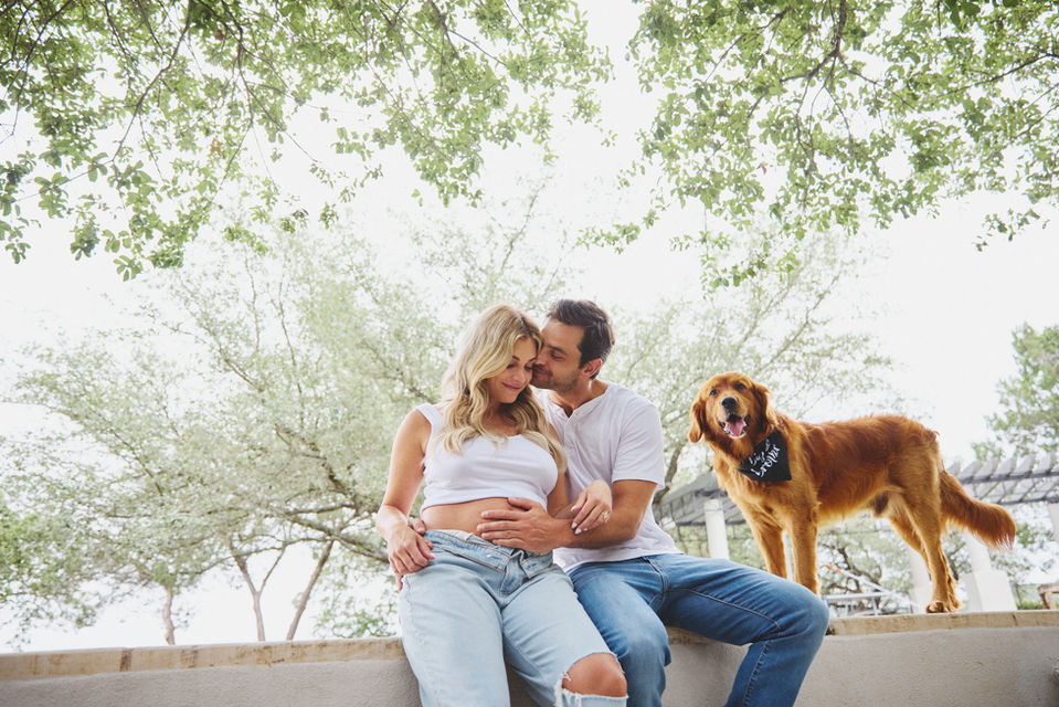 Maternity photography of an expecting couple relaxing together outdoors with their dog