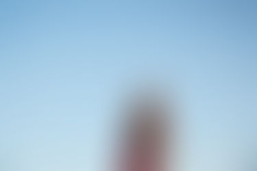 Couple standing together under a clear blue sky at McKinney Falls State Park in Austin, holding hands during their golden-hour photo session.