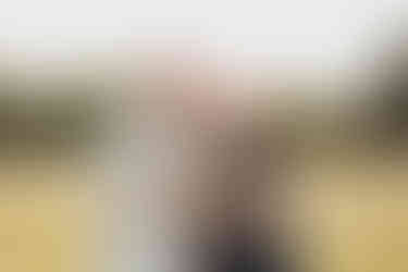 Family of three with a baby boy laughing in the park