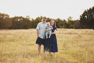 Family of three with a baby boy laughing in the park