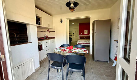 Cozinha integrada com mesa de jantar e churrasqueira interna.